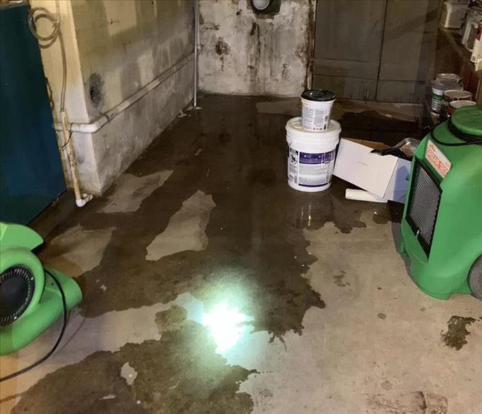 SERVPRO equipment in a basement that has water on the floor. 